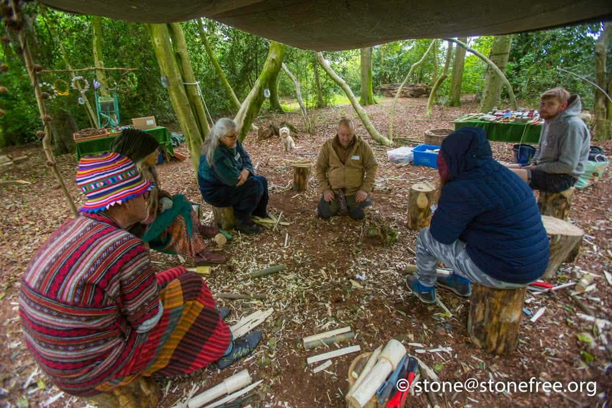 People sitting together in a woodland bushcraft area.